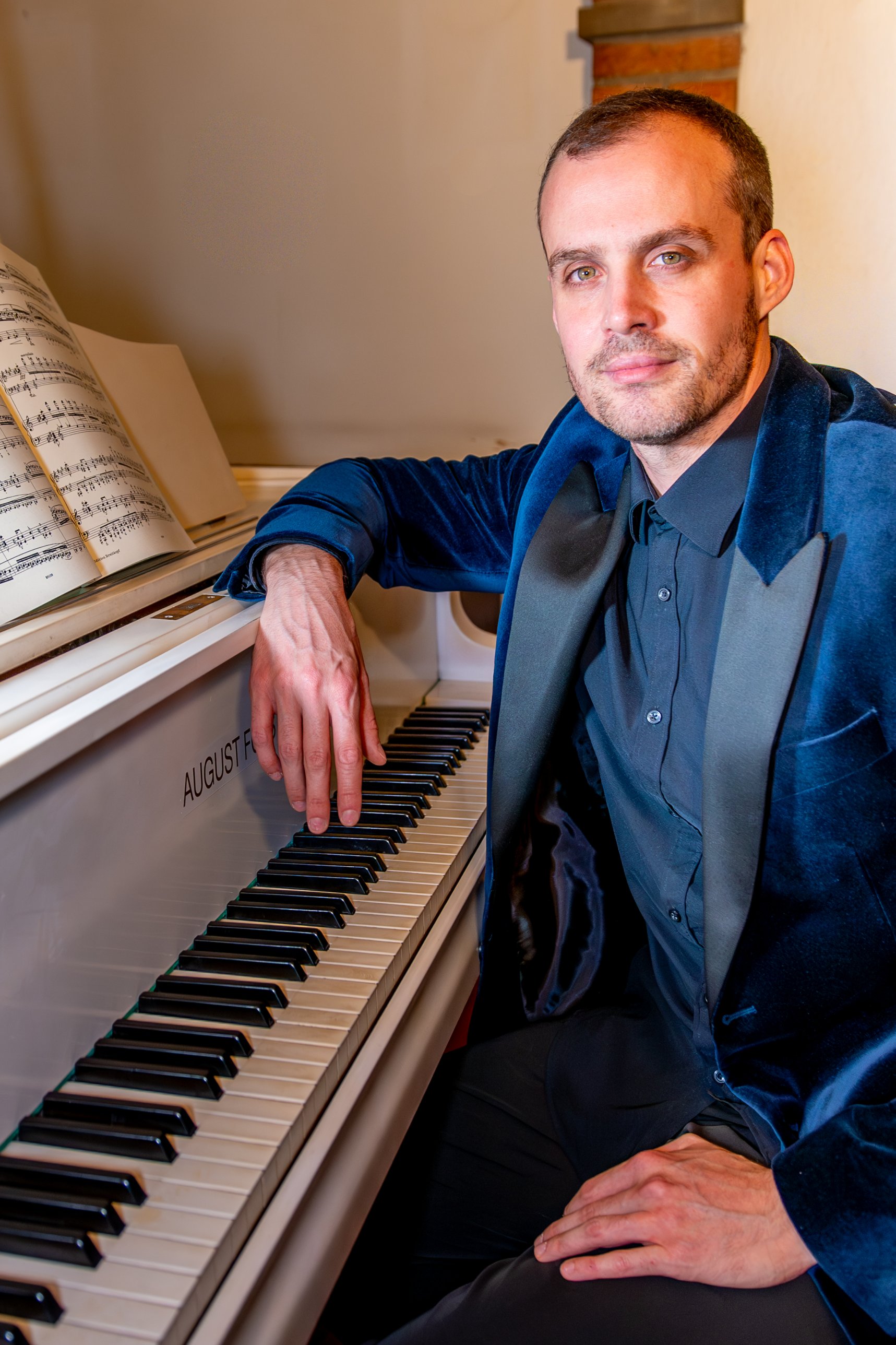 Pianist Ludovico Troncanetti seated at a grand piano